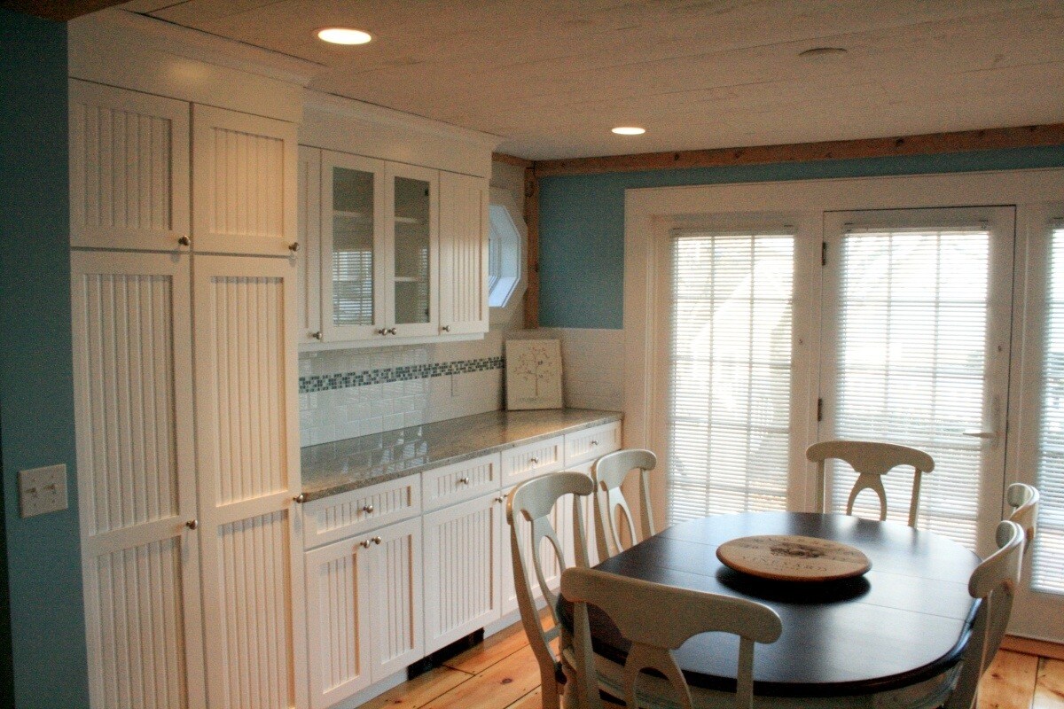 Custom kitchen with white cabinetry and glass-front cabinets in Mashpee by At Design Remodel