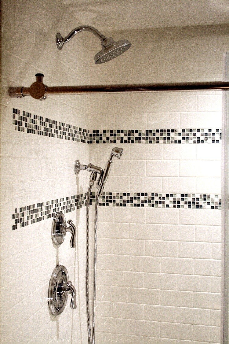 Glass tile shower with modern chrome fixtures in a Mashpee custom bathroom remodel by At Design Remodel