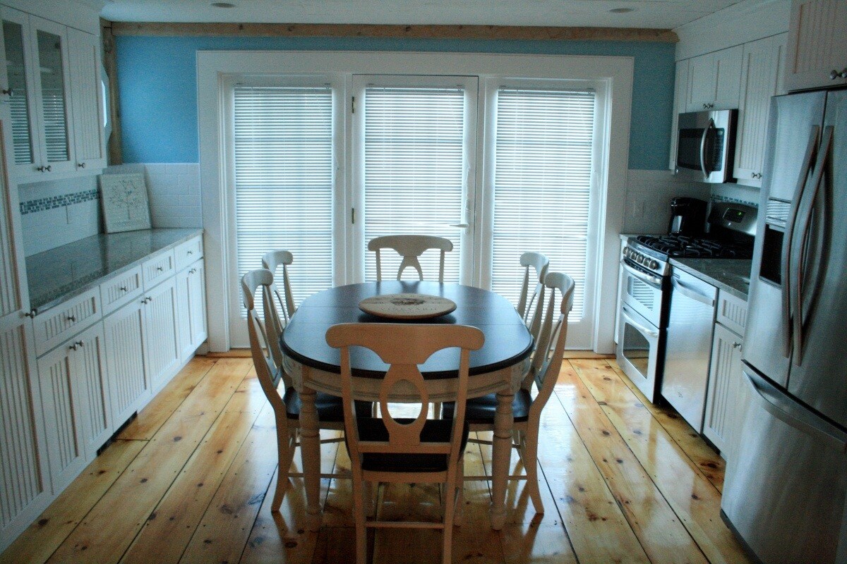 Light-filled Mashpee kitchen with wood floors and custom cabinetry by At Design Remodel