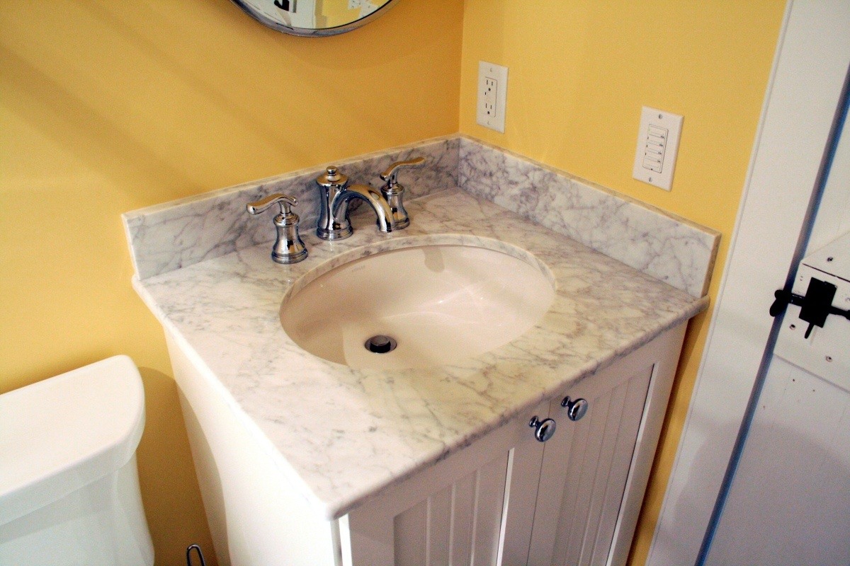 Marble countertop vanity with chrome faucets in a custom bathroom remodel by At Design Remodel, Mashpee