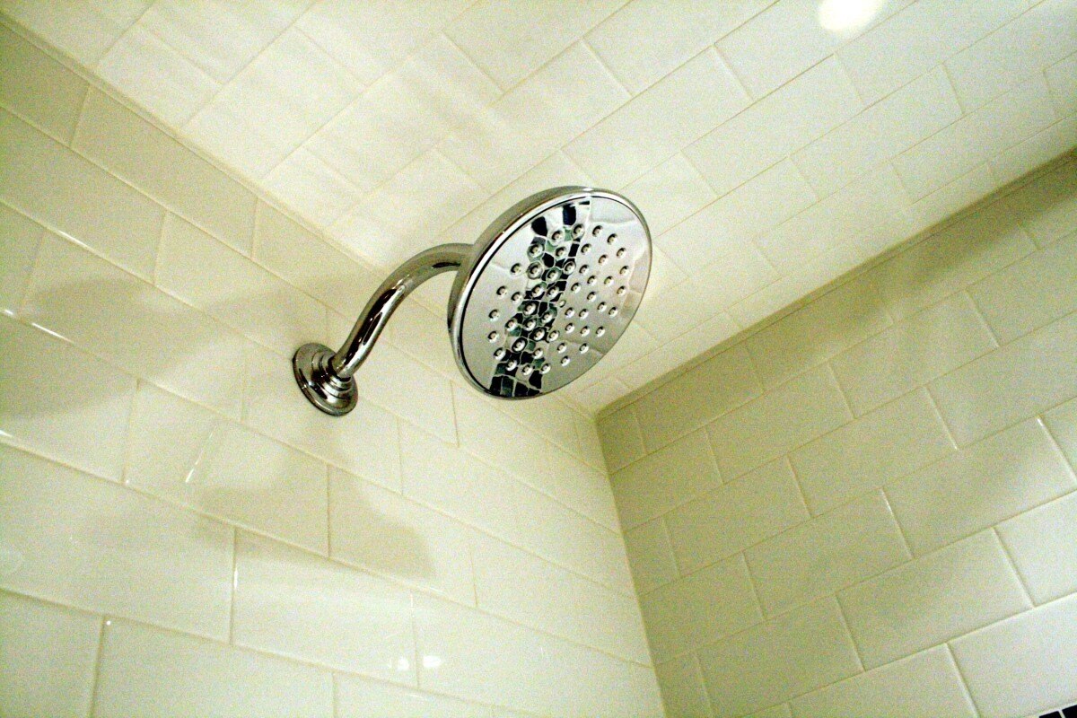 Sleek chrome showerhead set in white tiled bathroom for Maushop remodel, Mashpee