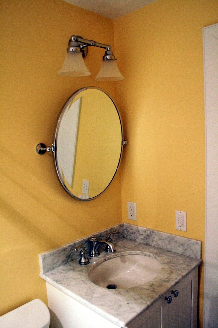 Yellow bathroom with marble vanity top and oval mirror in Maushop renovation