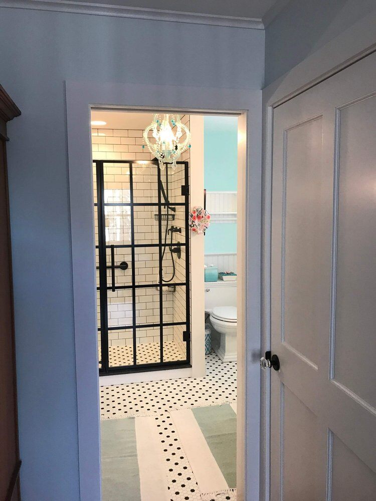 Entry view of remodeled bathroom featuring a black-framed glass shower, Bay Road Bath project in North Falmouth by At Design Remodel, Mashpee