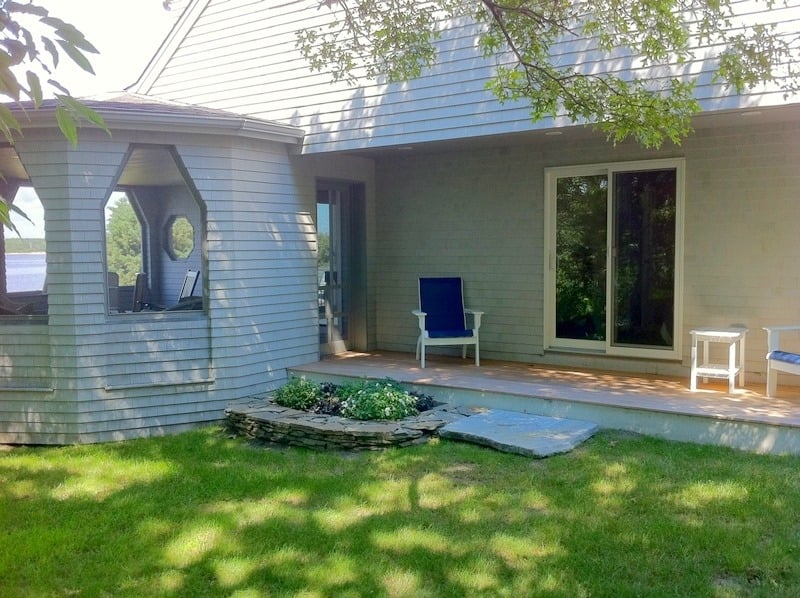 Backyard seating area of a Cataumet home with a shaded patio and garden