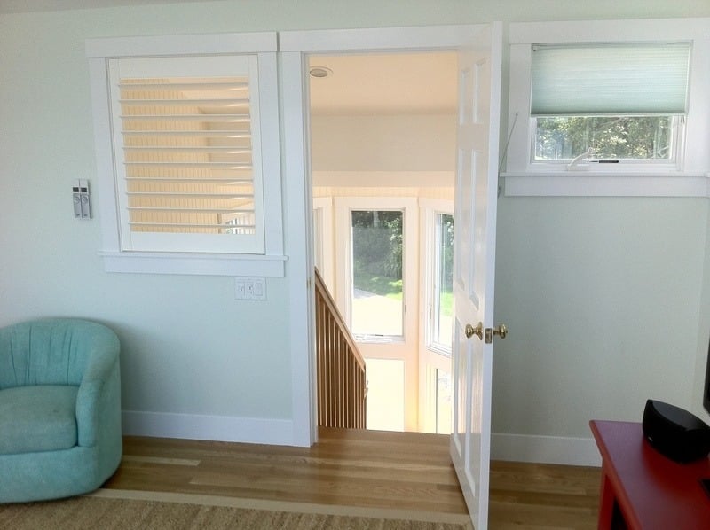 Bright stairwell with wood floors and large windows in a home remodel by At Design Remodel in Cataumet, Mashpee