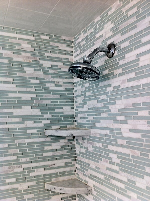 Chrome shower fixtures and glass shelf in a remodeled bathroom by At Design Remodel in Cataumet