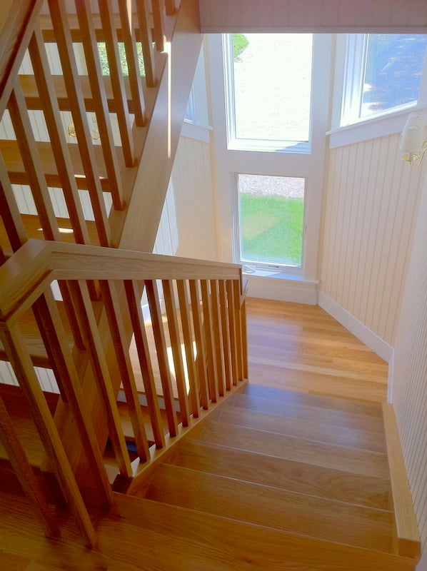 Custom wood staircase with natural lighting from large windows in a renovated Cataumet home