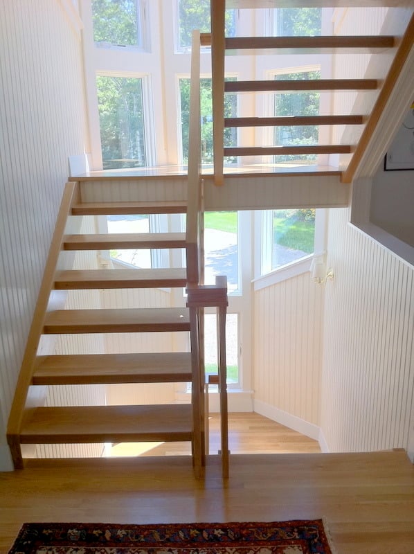 Detail view of modern wooden stair handrail in a Cataumet home renovation by At Design Remodel