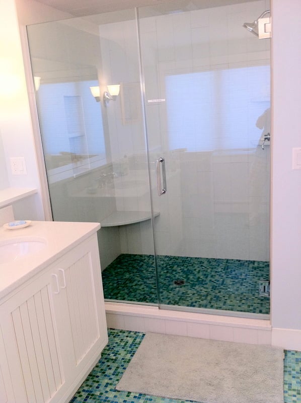 Vanity and shower area with glass enclosure in a remodeled bathroom by At Design Remodel in Cataumet