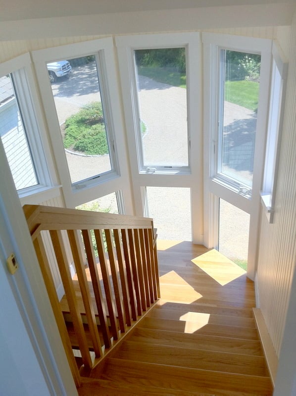 Wooden staircase and windows overlooking a driveway in a Cataumet home improvement project by At Design Remodel