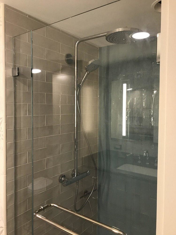 Rain showerhead and tiled wall in Centerville bathroom renovation by At Design Remodel in Mashpee