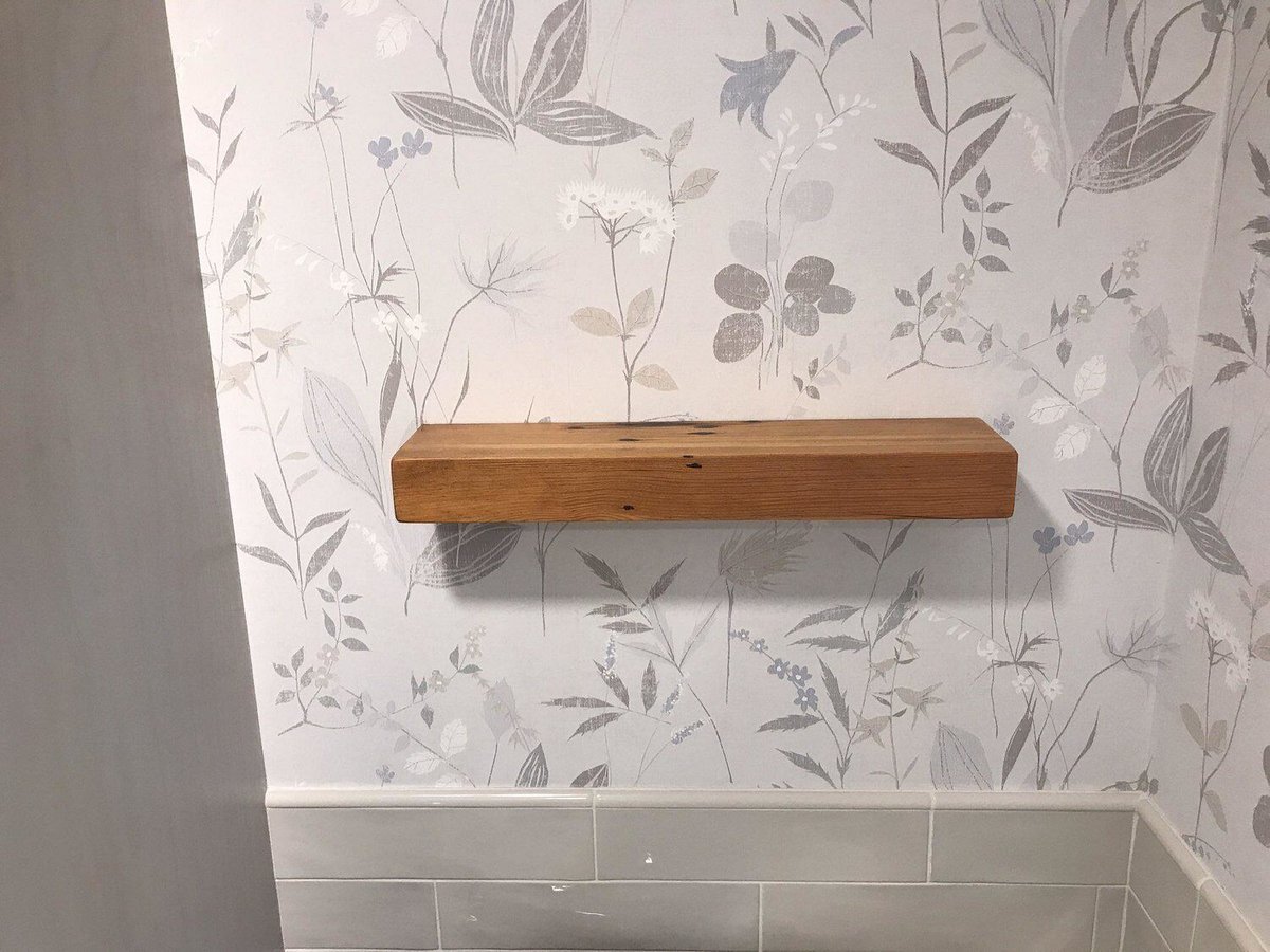 Wooden shelf against floral wallpaper in Centerville bathroom remodel by At Design Remodel in Mashpee