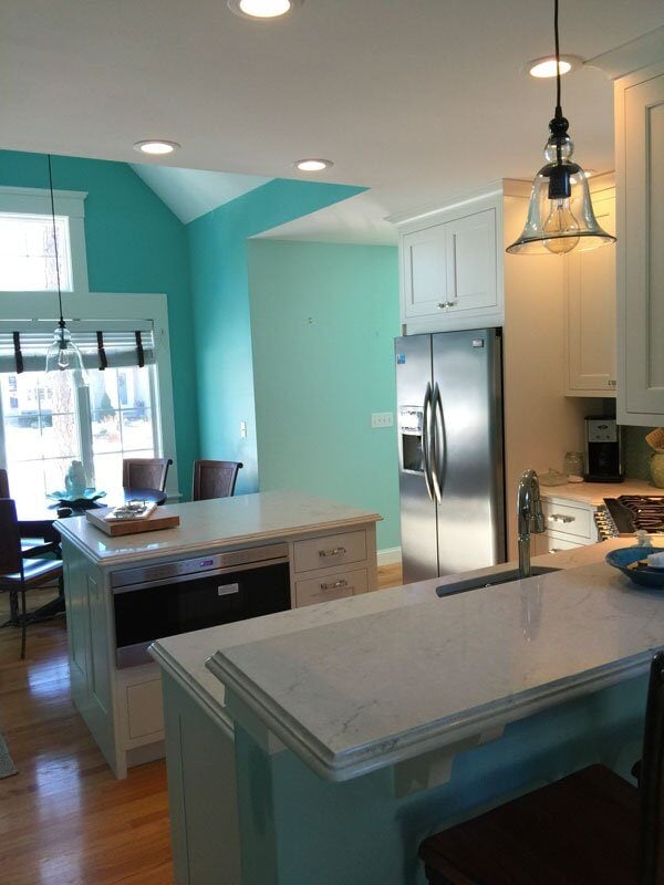 Marble countertops with a sleek sink and turquoise backsplash in a Cotuit kitchen remodel by At Design Remodel