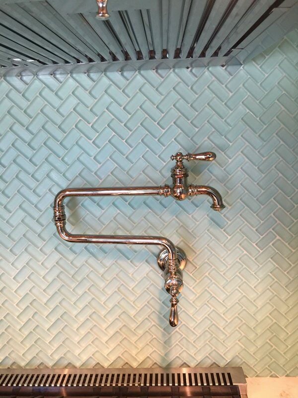 Stylish copper faucet in a Mashpee kitchen remodel by At Design Remodel, featuring a herringbone turquoise backsplash