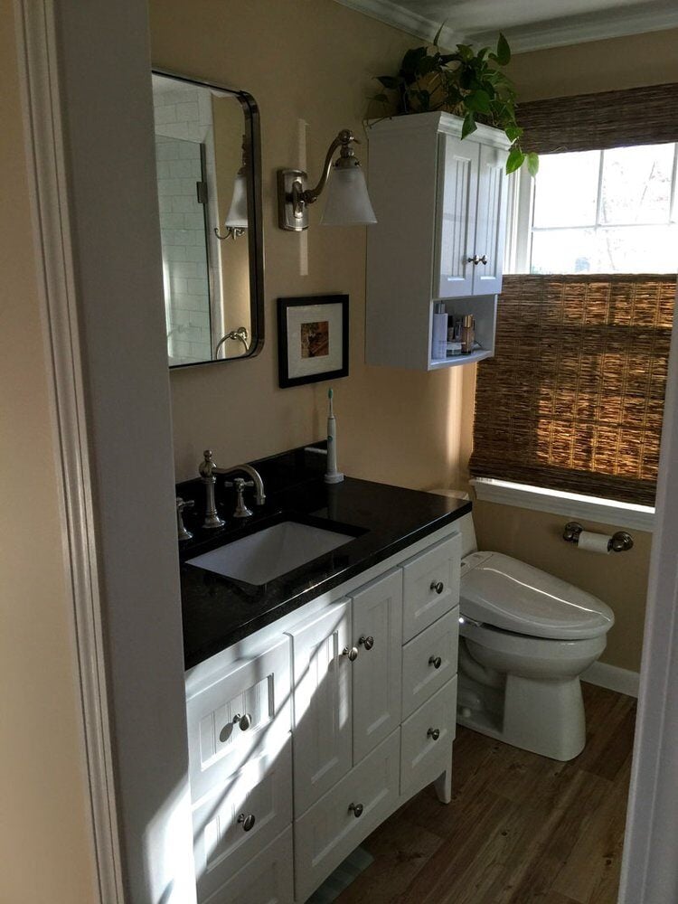 Falmouth bathroom renovation featuring white cabinetry, black vanity, and a serene atmosphere by At Design Remodel in Mashpee