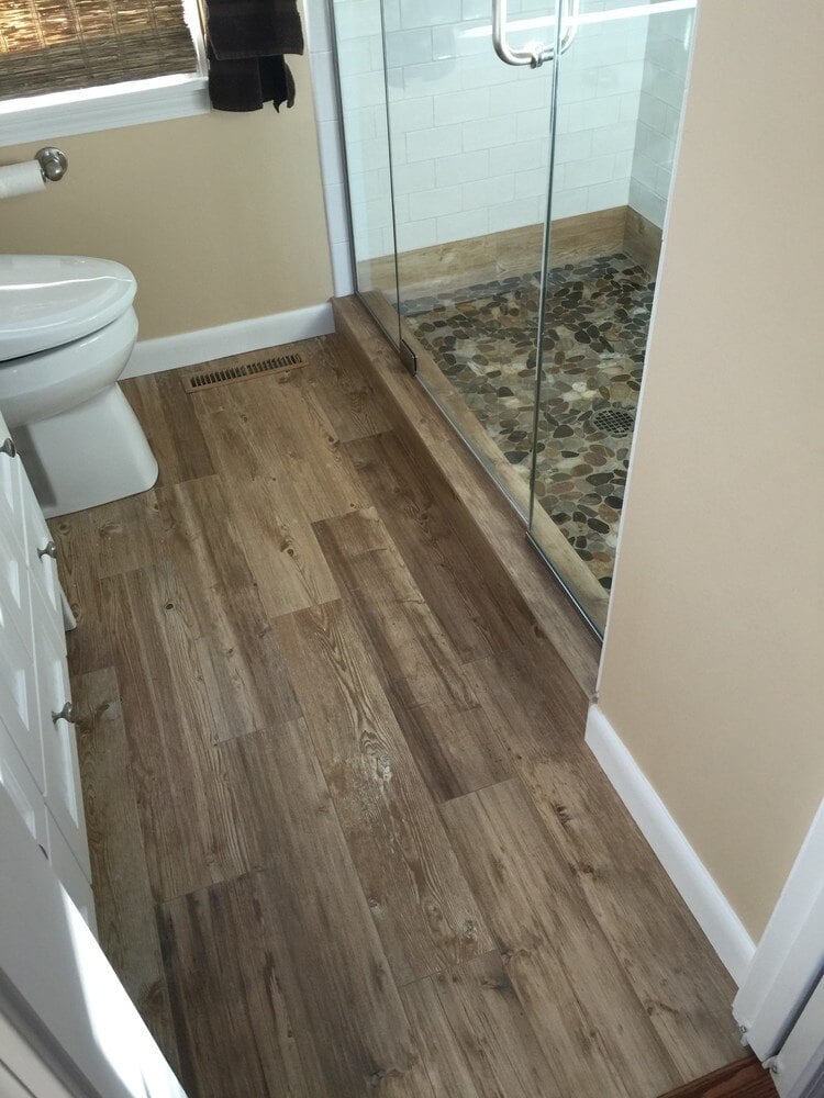 Modern bathroom flooring with wooden tile design and walk-in shower by At Design Remodel in Mashpee