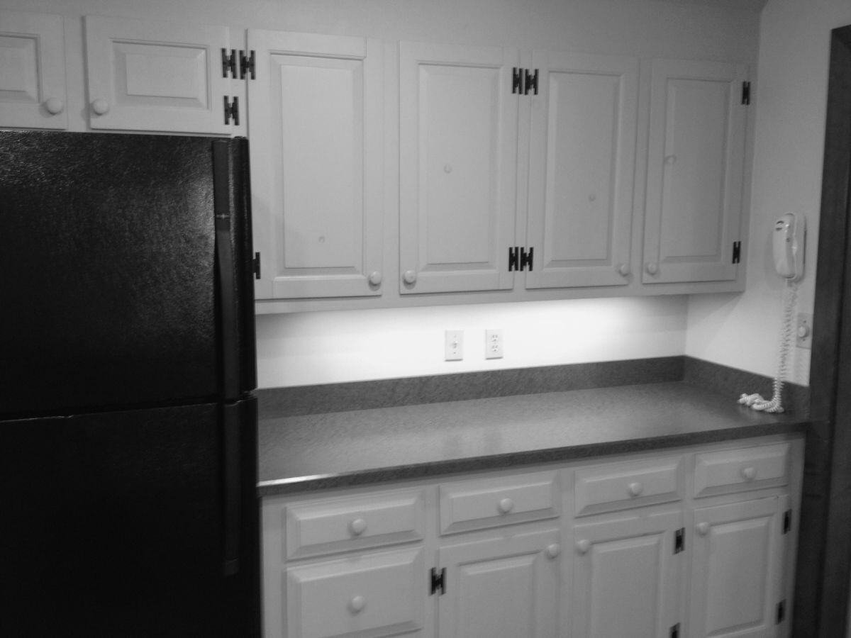 Before image of a kitchen with white cabinetry and black refrigerator in Falmouth