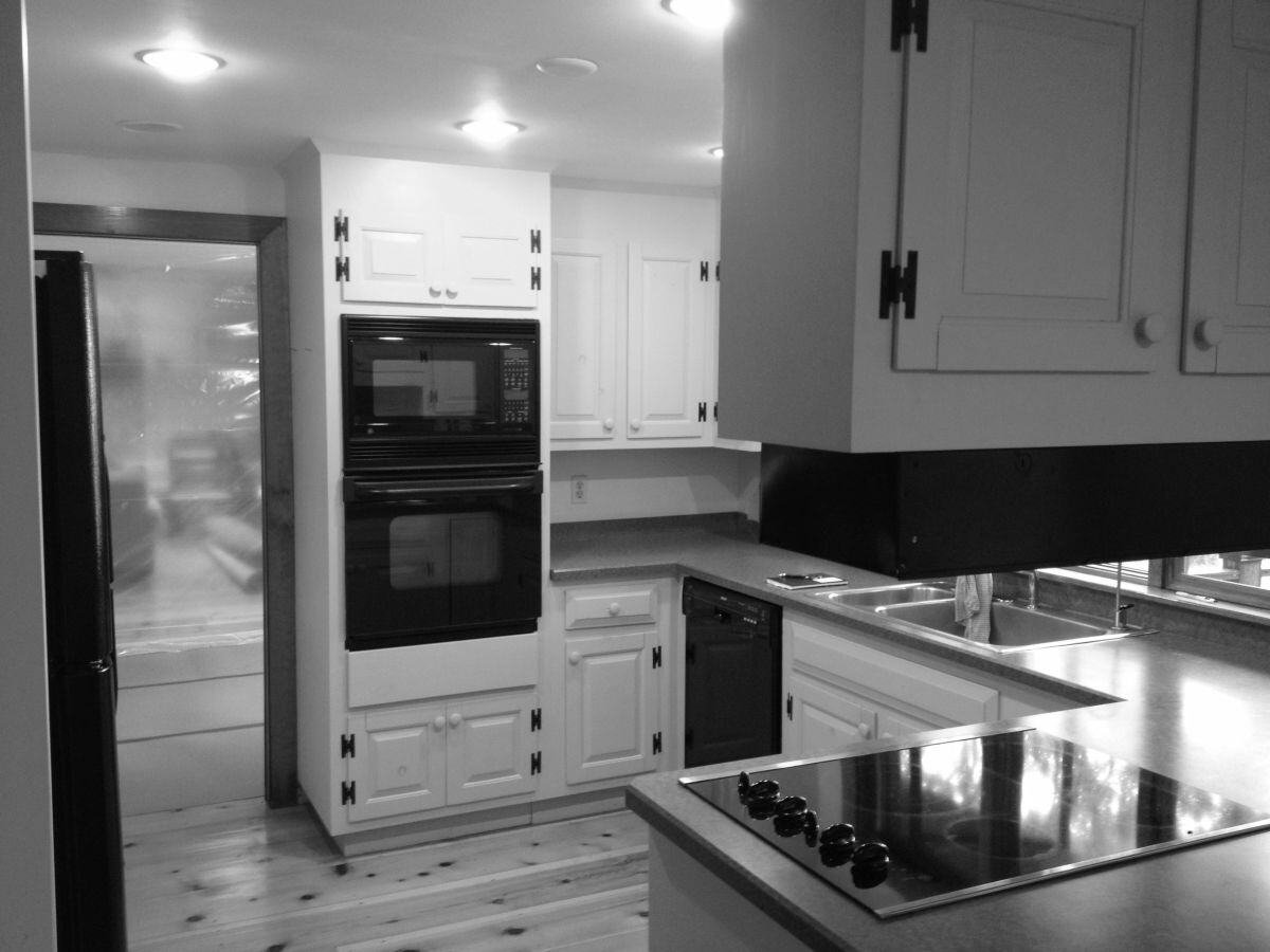 Falmouth kitchen prior to remodel, with dated white cabinets and black stovetop