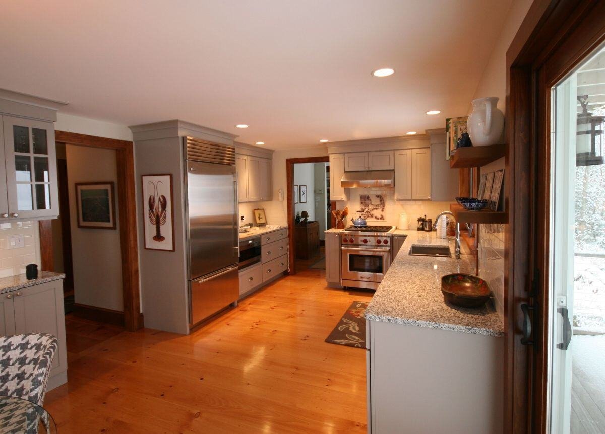 Open layout kitchen with modern appliances and light wood flooring in a Falmouth home