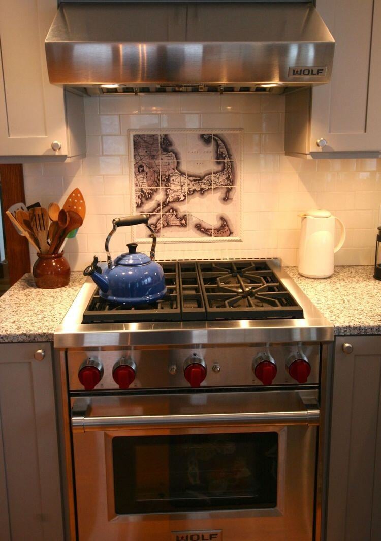 Stainless steel stove with a detailed backsplash map in a Falmouth kitchen renovation by At Design Remodel