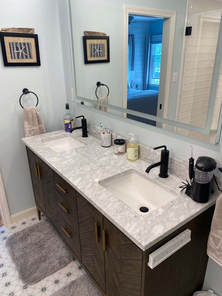 Double vanity with marble countertop and modern fixtures in master bathroom remodel by At Design Remodel, Dennis, MA