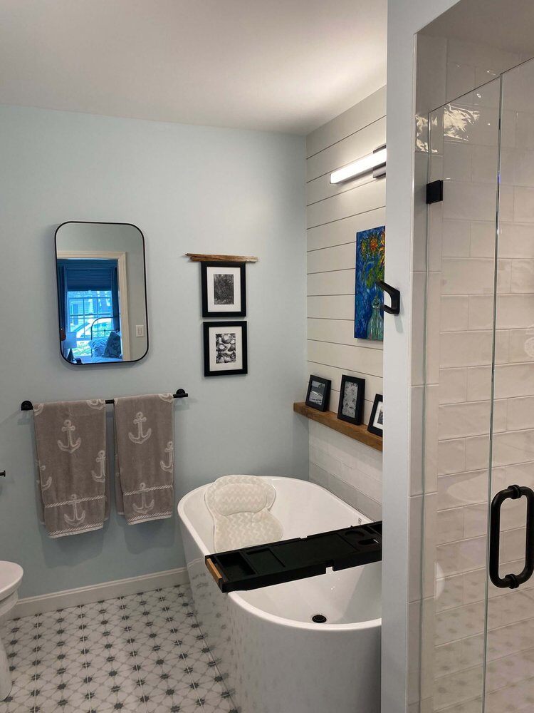 Freestanding tub with shiplap wall accents in newly remodeled master bathroom by At Design Remodel, Dennis, MA