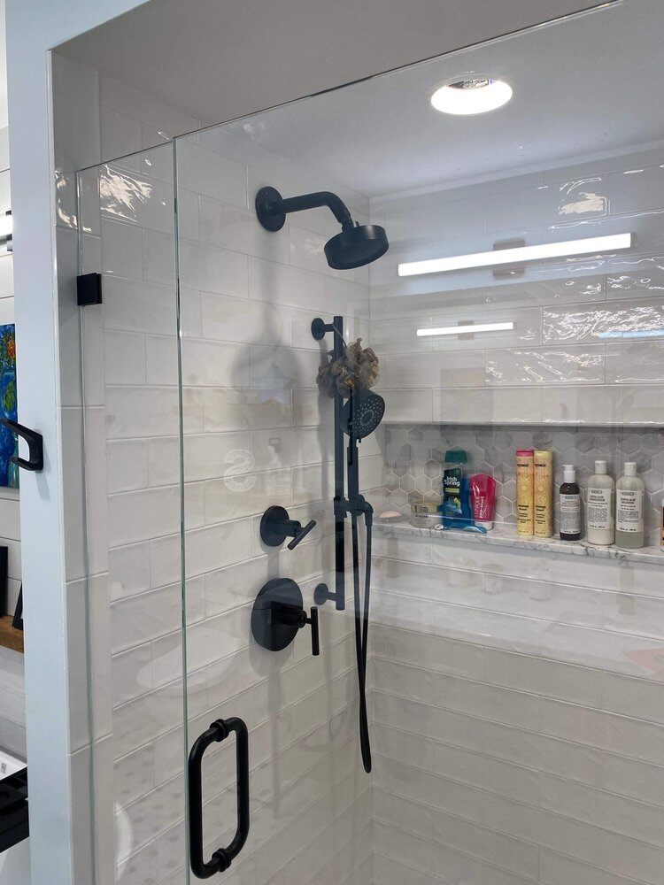 Shower remodel with glass door and black fixtures in luxury custom home by At Design Remodel, Dennis, MA