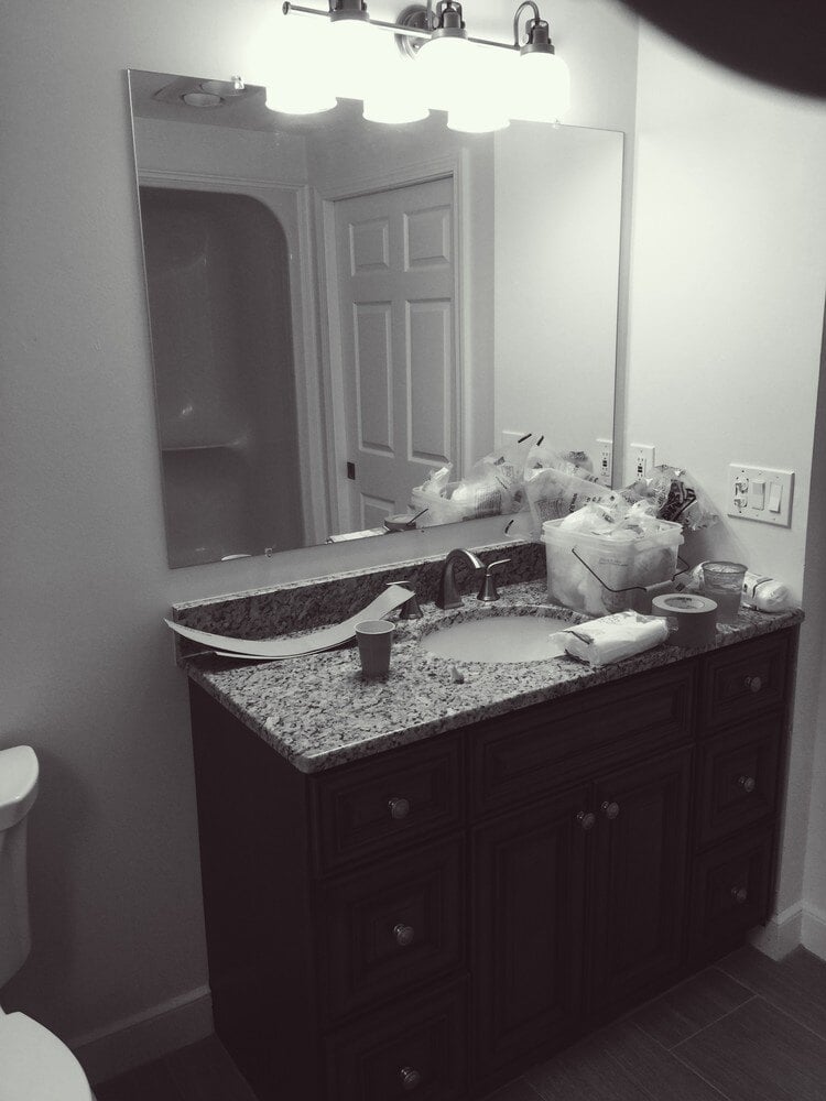 Granite countertop vanity with lighting fixtures in a Mashpee bathroom remodel by At Design Remodel