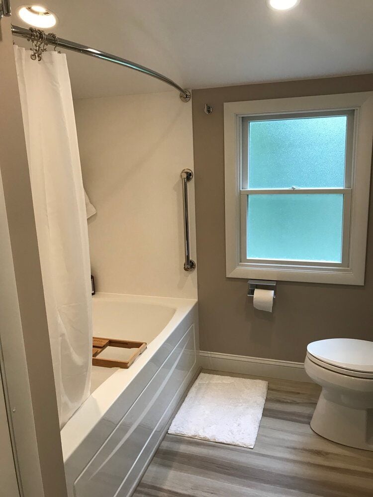 Contemporary bathroom design with updated bathtub and window by At Design Remodel on Treasure Lane, Mashpee