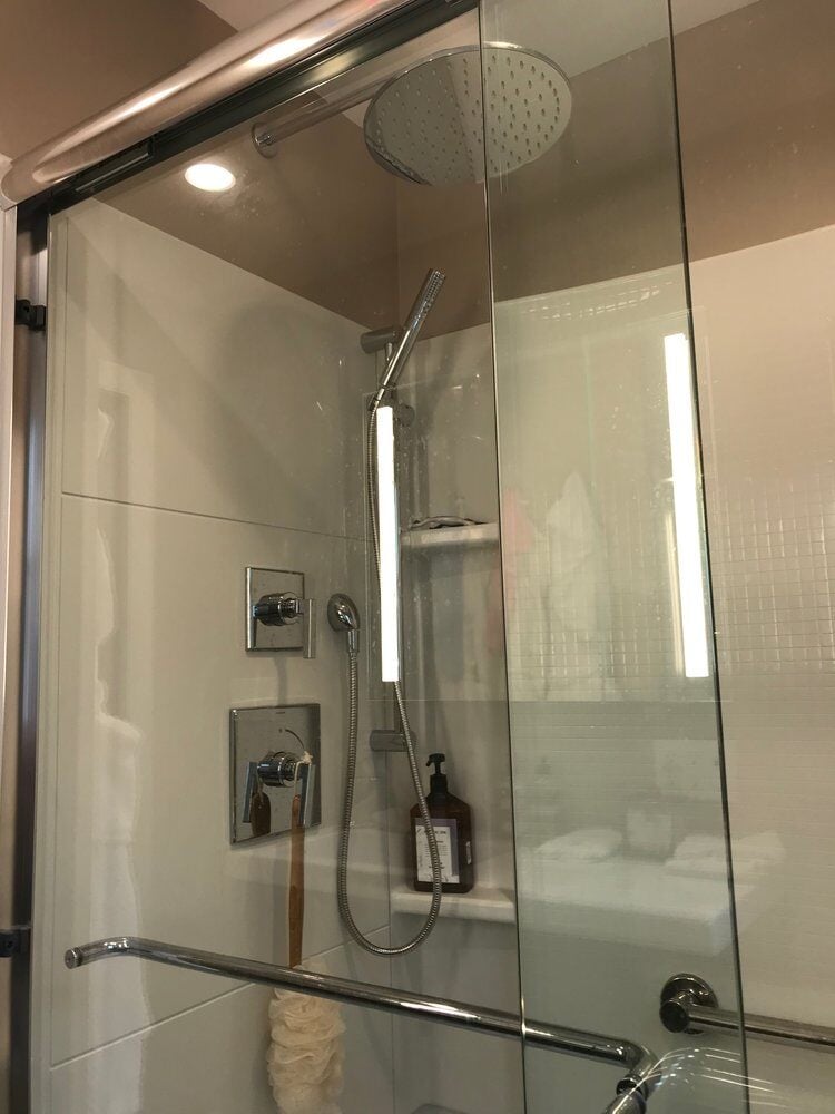 Renovated shower with rainfall shower fixture and glass doors in a Treasure Lane project by At Design Remodel