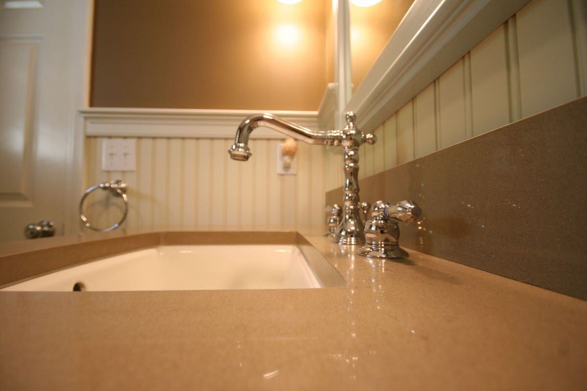 Chrome faucet and beige countertop in newly remodeled Mashpee bathroom by At Design Remodel