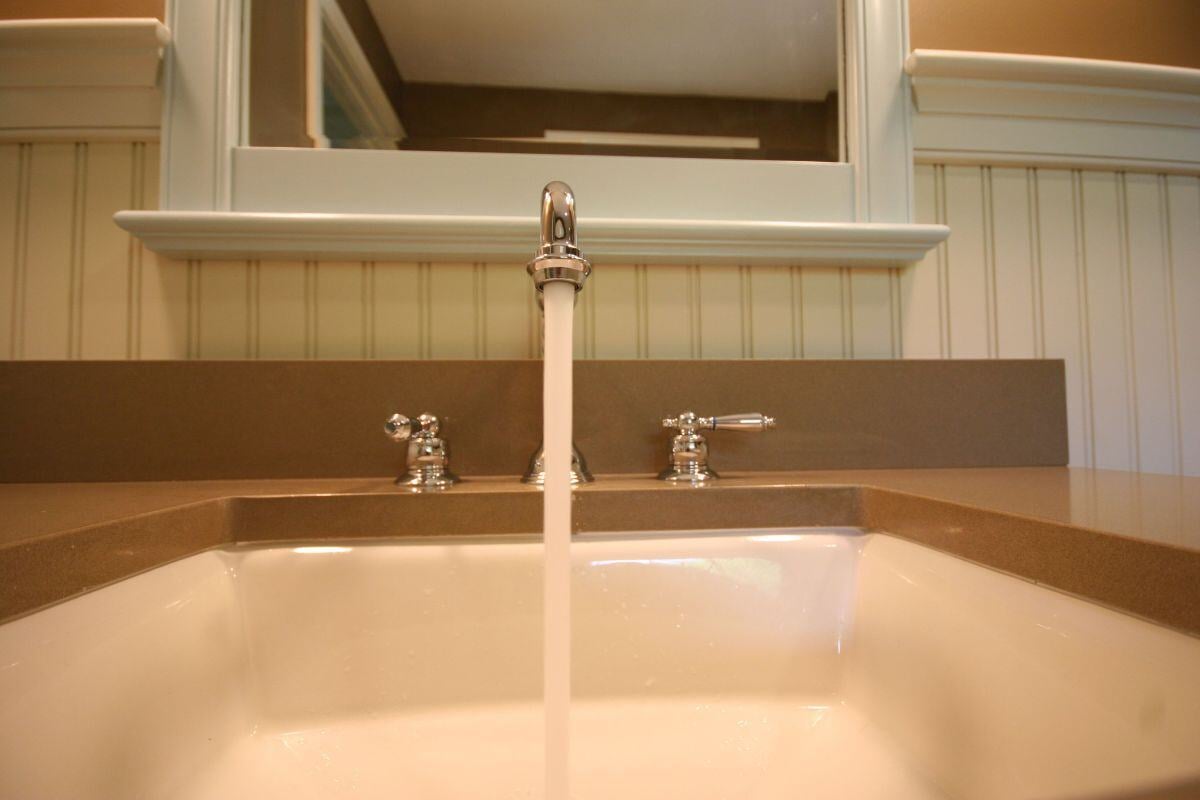 Running water from faucet in remodeled Mashpee bathroom by At Design Remodel