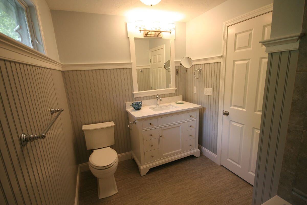 White bathroom vanity with mirror and modern lighting in Mashpee bathroom remodel by At Design Remodel