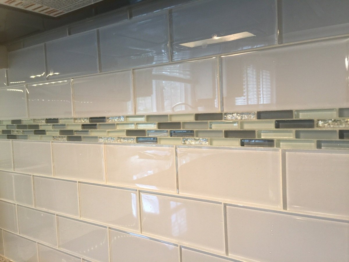 Detailed view of tile backsplash with mosaic design in renovated Mashpee kitchen by At Design Remodel