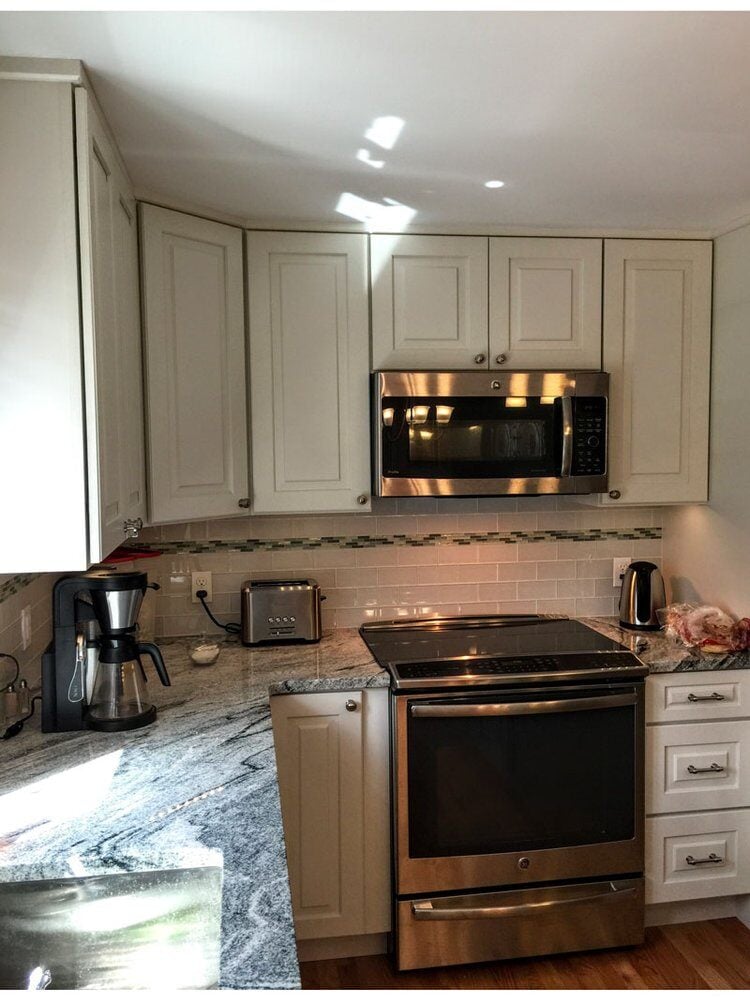 Fully remodeled kitchen in Mashpee with white cabinetry, stainless steel oven, and modern design by At Design Remodel