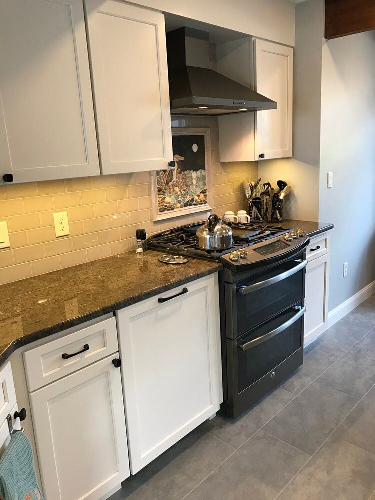 Kitchen remodel featuring white cabinetry, granite countertops, and a stainless steel range by At Design Remodel in Mashpee