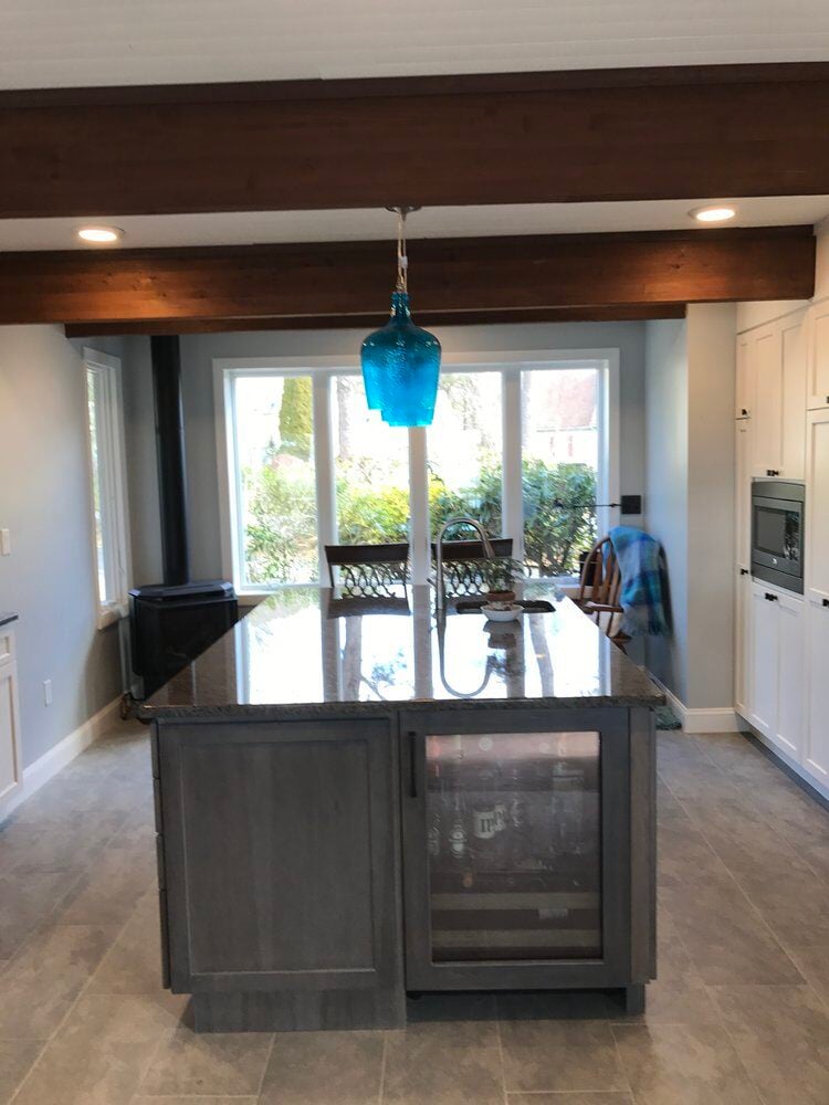 Modern kitchen island with granite countertop and blue pendant light by At Design Remodel in Mashpee