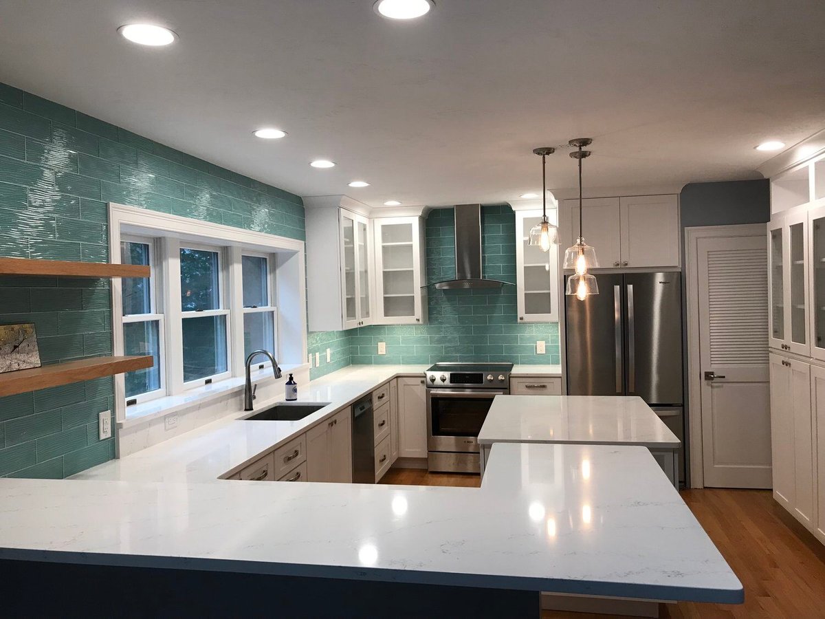 Brightly lit kitchen remodel featuring white countertops and teal backsplash, completed by At Design Remodel in Mashpee