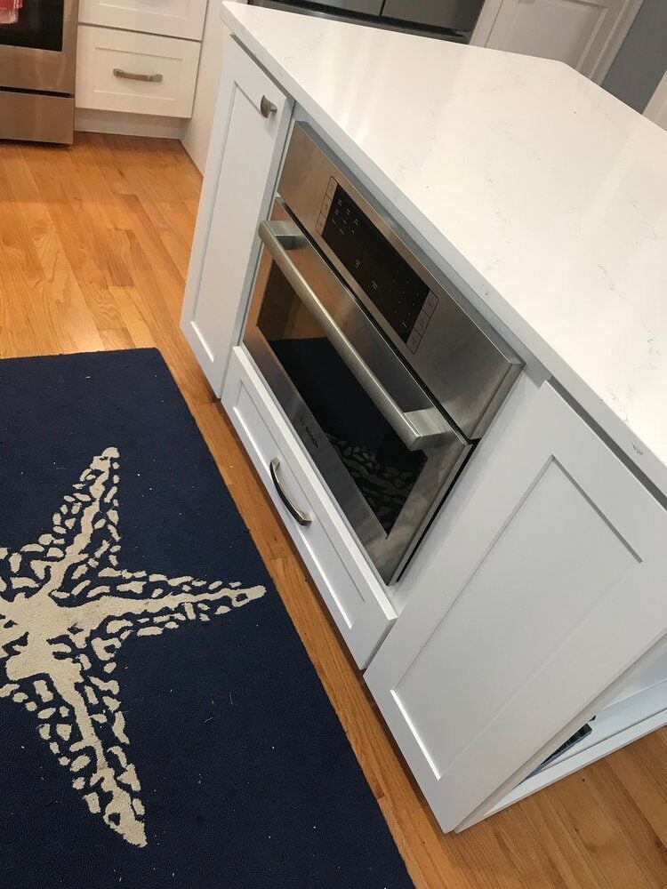 Center island with built-in bookshelf in Mashpee kitchen remodel by At Design Remodel