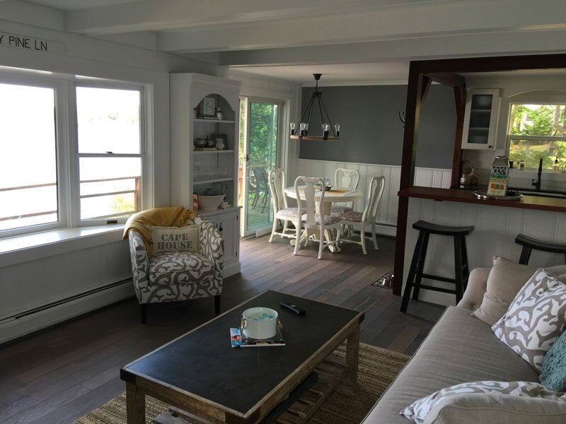 Living and dining space with wooden beams and lake views, part of a Mashpee cottage renovation by At Design Remodel