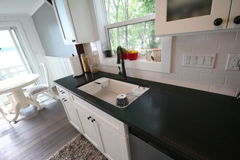 Modern kitchen sink and countertop with a window view of the lake, part of Mashpee Lake Cottage remodel by At Design Remodel