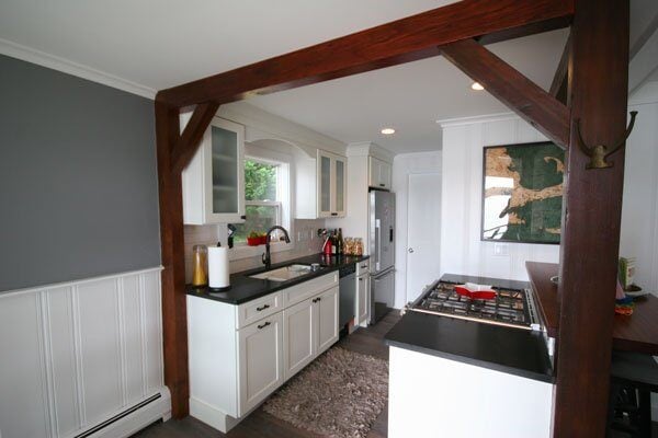 Open-concept kitchen featuring wood beams and modern cabinetry in a Mashpee lakefront cottage remodel by At Design Remodel