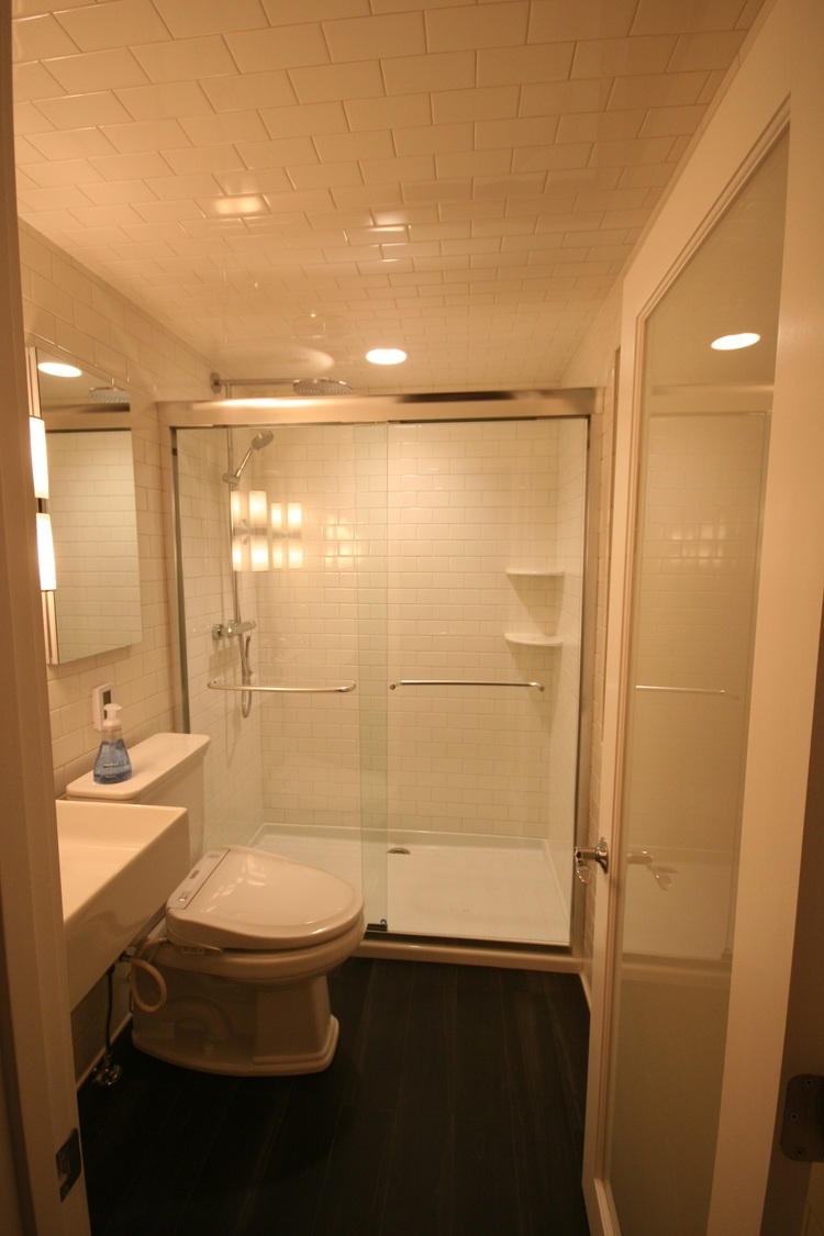 Clean and sleek bathroom remodel featuring a white subway-tiled shower with glass doors in Mashpee by At Design Remodel