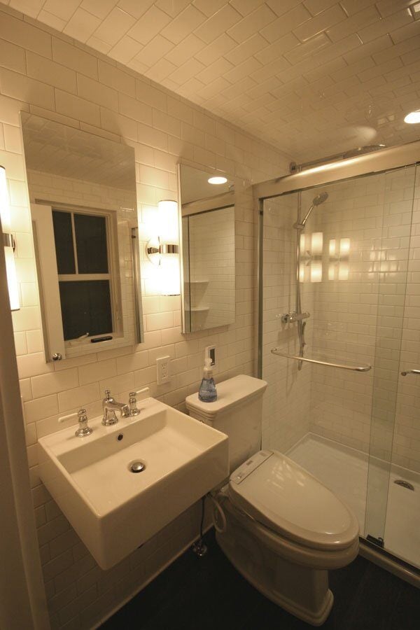 Compact modern bathroom with white subway tile, glass-enclosed shower, and vanity in a Mashpee remodel by At Design Remodel