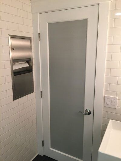 Frosted glass bathroom door with white subway-tiled walls in a Mashpee bathroom remodel by At Design Remodel