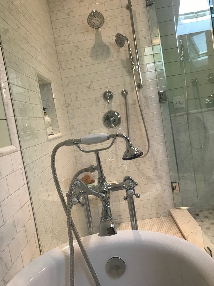 Chrome faucet and clawfoot tub in New Seabury bathroom remodel with glass shower nearby.