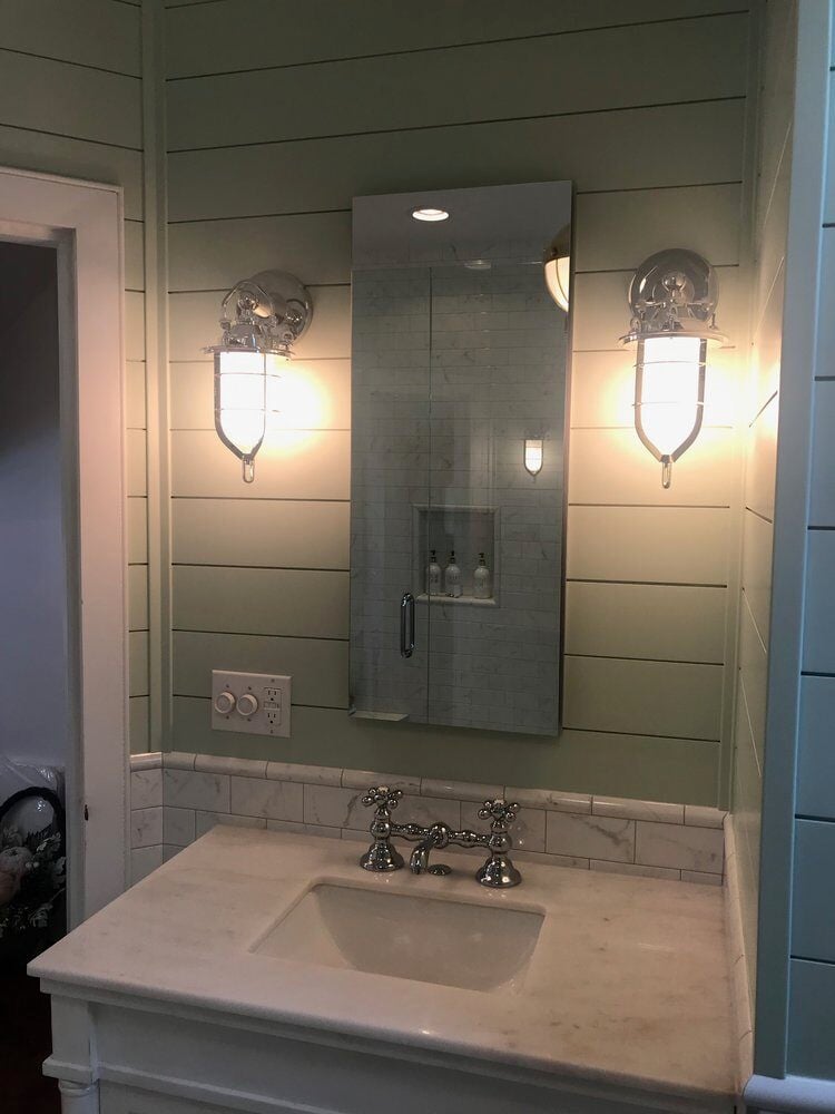 White marble vanity with chrome fixtures and nautical lighting in New Seabury bathroom remodel