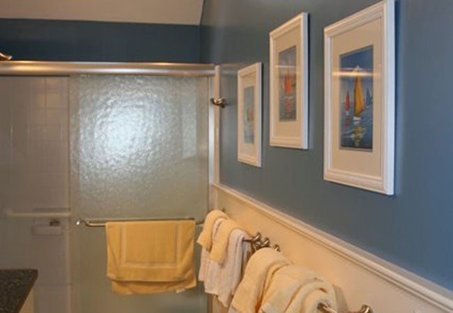 Completed bathroom with blue walls and framed sailboat artwork in New Seabury by At Design Remodel, Mashpee