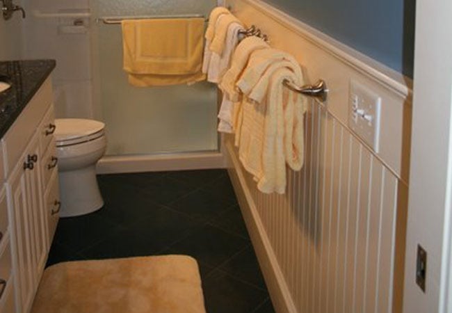 Finished bathroom with black tiles and yellow towels in New Seabury remodel by At Design Remodel, Mashpee