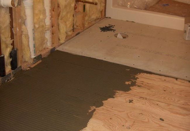 Tile adhesive applied on floor during New Seabury bathroom remodel by At Design Remodel, Mashpee